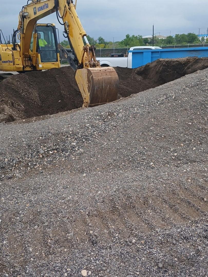 Double DD LLC excavator on a San Antonio jobsite working a graded gravel pad