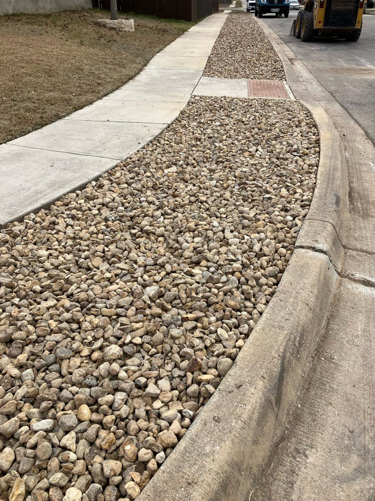 Finished xeriscaping — river rock installed along sidewalk and curb